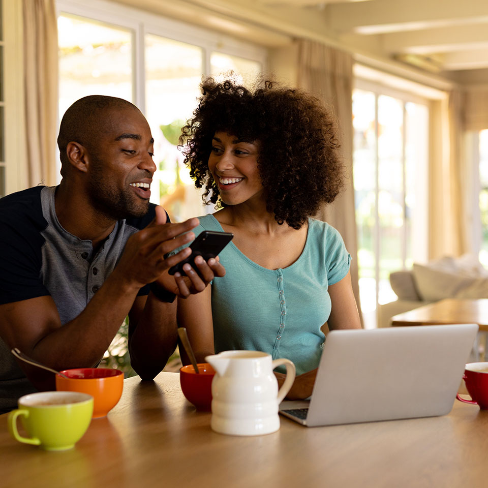 Image showing a happy couple on the phone in front of their laptop