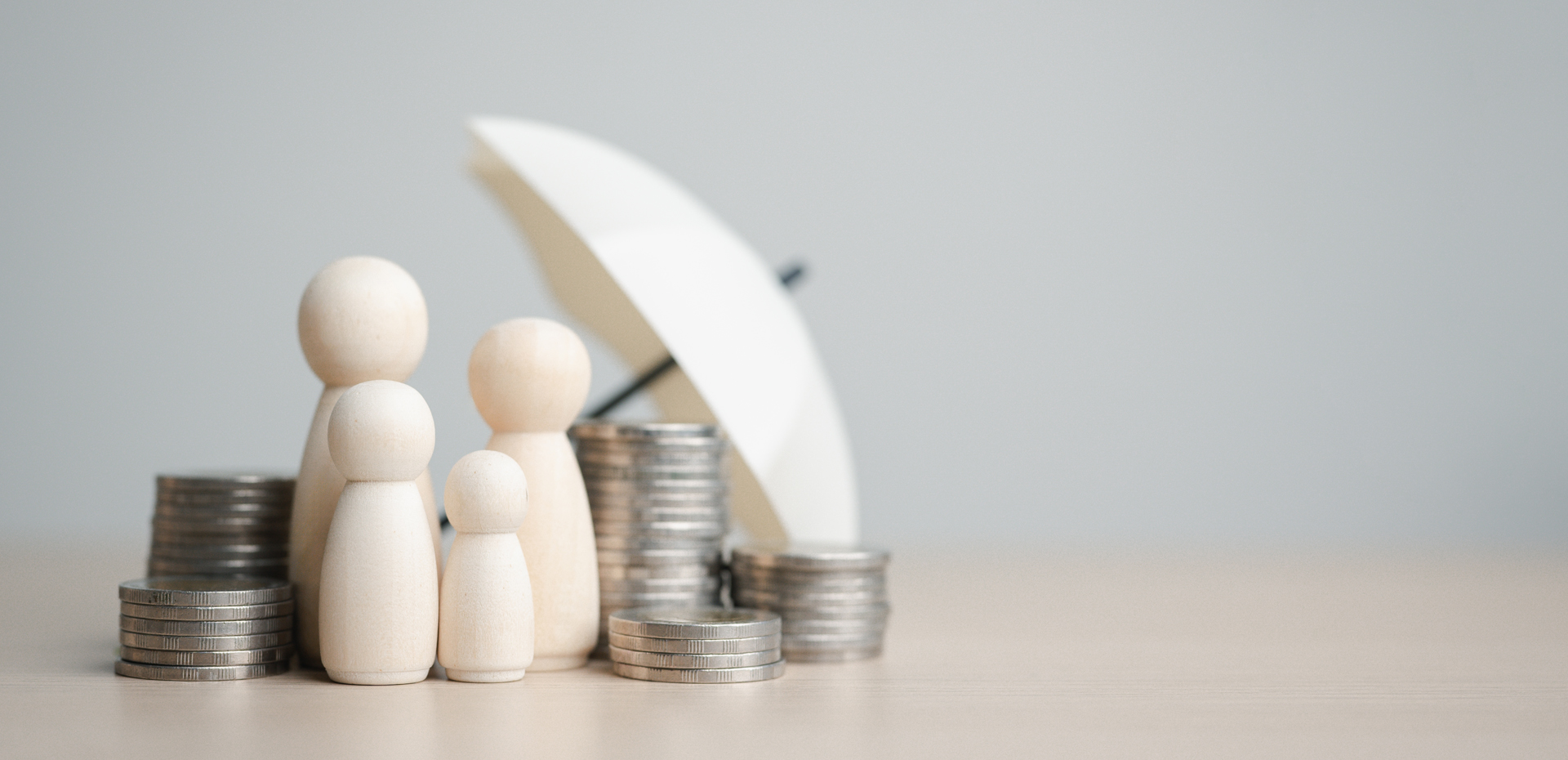 image showing wooden family protected by an umbrella with coins on the side
